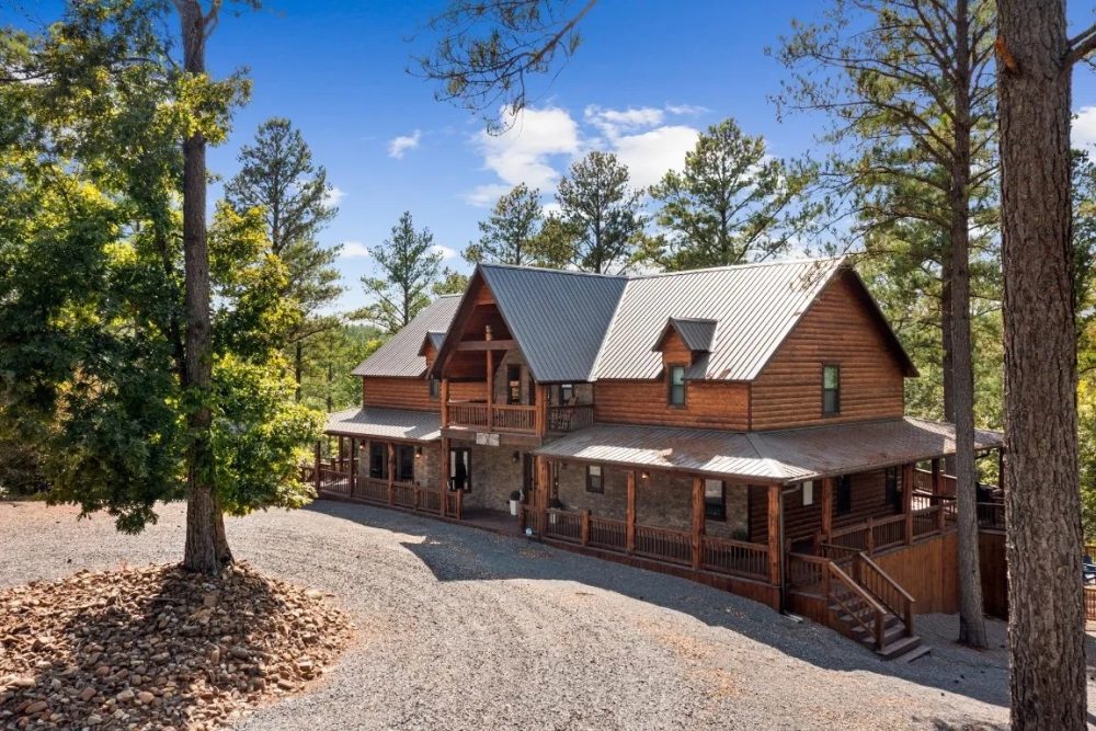 Cozy cabin surrounded by trees in Broken Bow, OK, featuring a wooden exterior, spacious porch