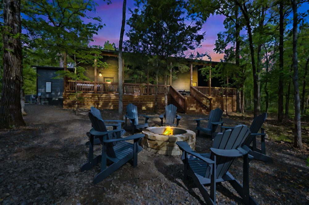 Luxury cabin retreat in Broken Bow, Oklahoma, featuring a stone fire pit surrounded by Adirondack