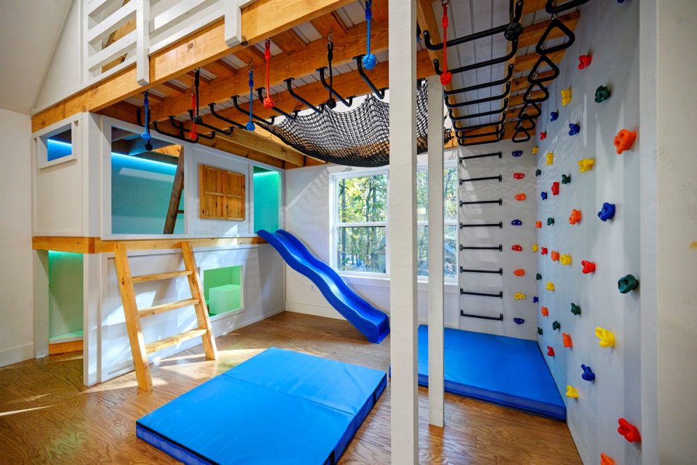 Indoor kids' play area with climbing wall, rope net, and slide inside a luxury cabin