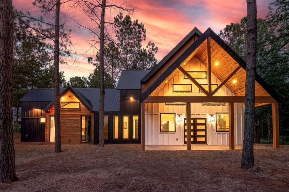 Luxurious Broken Bow cabin with a gabled roof and large windows, illuminated warmly