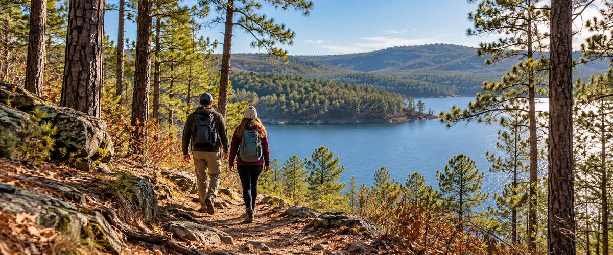 Two hikers on a pine forest trail overlooking a lake near Hochatown
